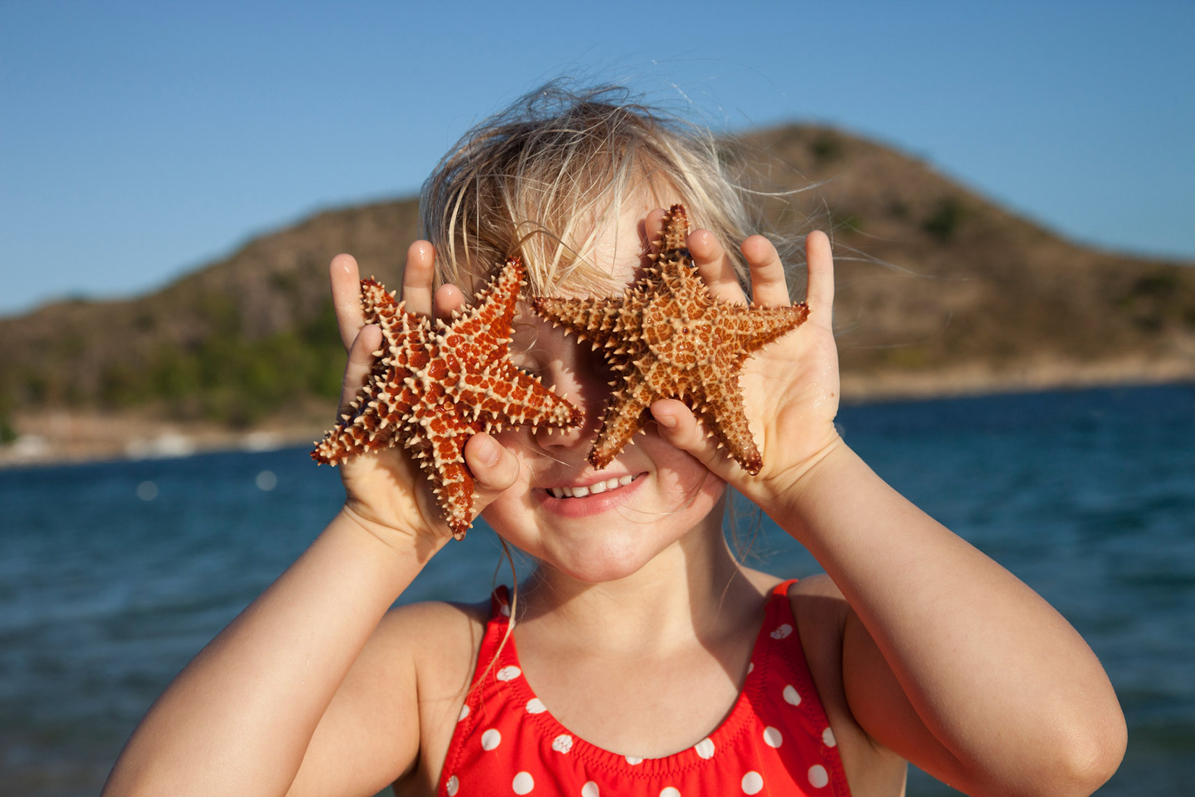 A-YOUNG-GIRL-HOLDING-STARFISH-OVER-HER-EYES