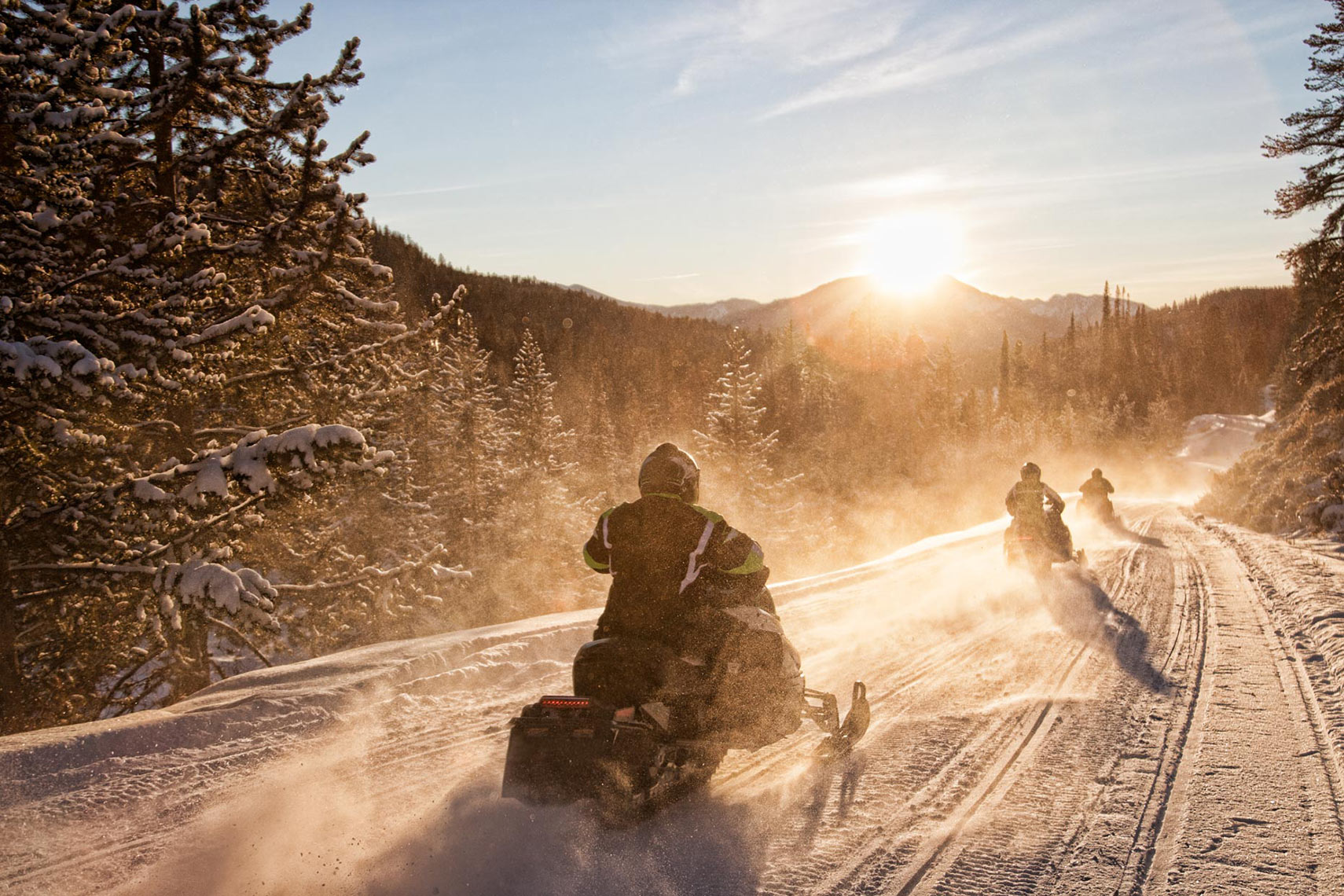 GROUP-OF-SNOWMOBILES-RIDING-INTO-SUNSET